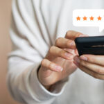 Close-up of a person using a smartphone to leave a five-star patient review