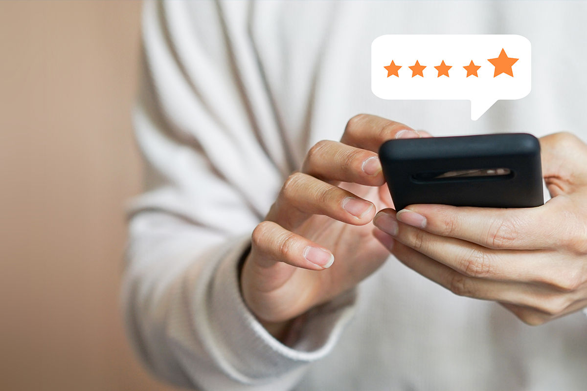 Close-up of a person using a smartphone to leave a five-star patient review