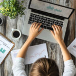 Top-down view of a person analyzing digital marketing data on a laptop, surrounded by printed charts and graphs, symbolizing AI-driven orthopedic marketing trends.